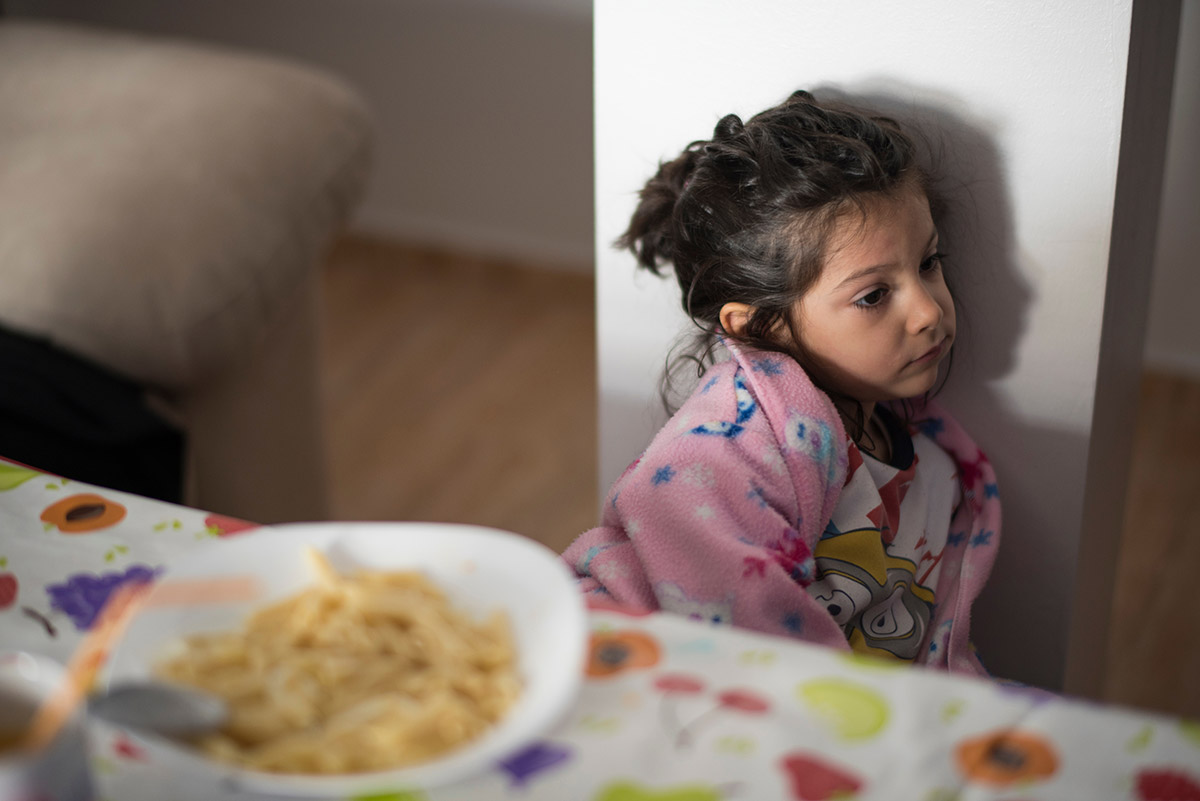 Child sad because her ear hurts can't eat and rejects bowl of food in the foreground